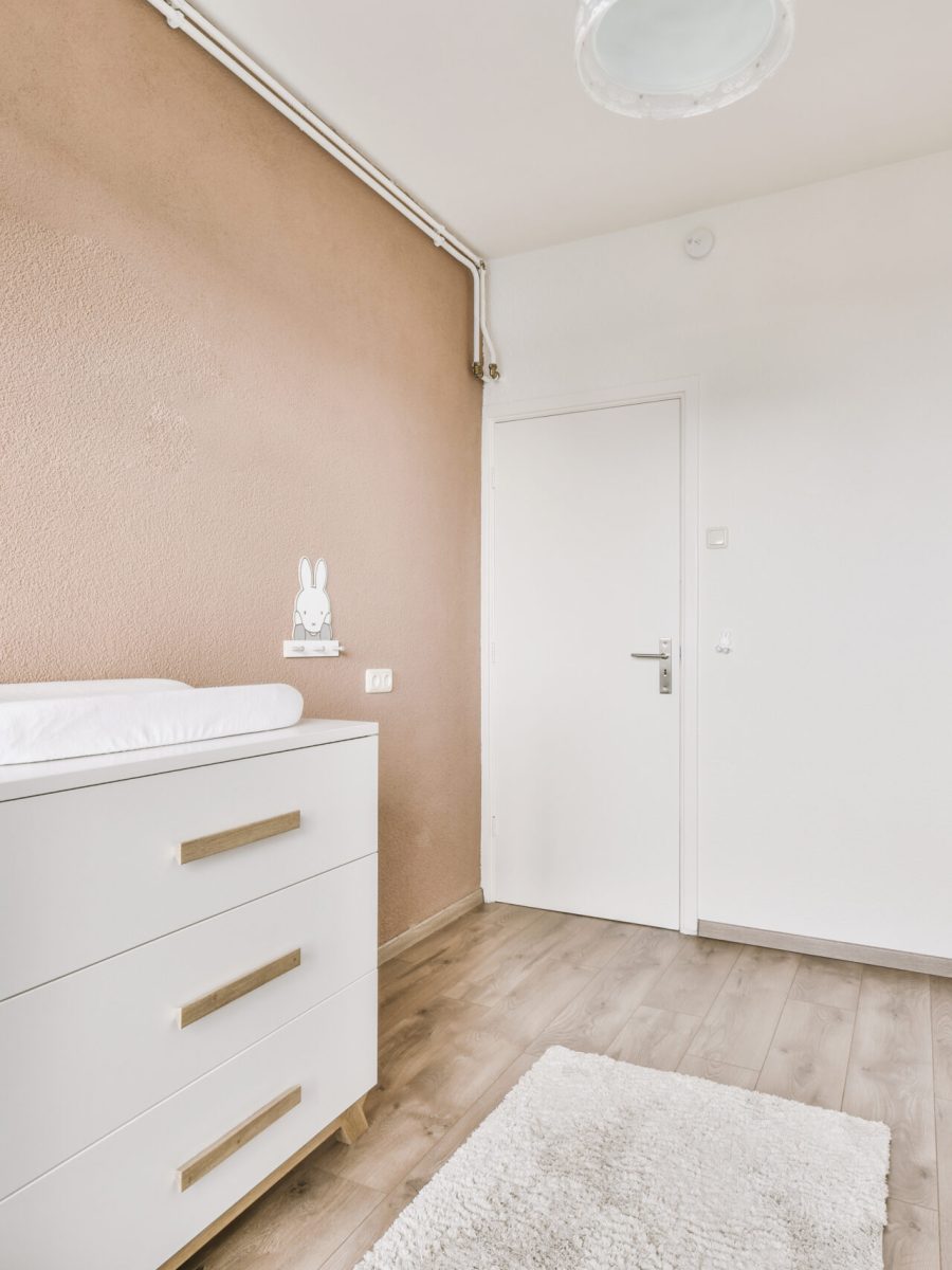 Minimalist interior design of small bedroom with soft bed placed in corner and wooden wardrobe and shelves with lamp illumination